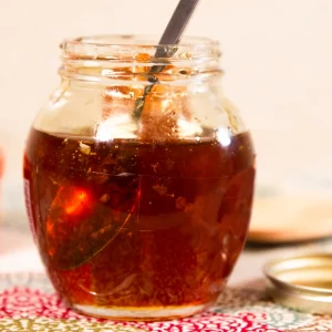 Vasetto di vetro con miele ambrato e cucchiaino